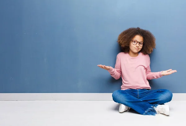 アフリカ系アメリカ人の少女は困惑し混乱し正しい答えや決断がわからず床に座ることを選択しようとします — ストック写真
