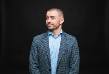 Genç işadamı merak ediyor, mutlu düşünceler ve fikirler düşünüyor, hayal kuruyor, düz duvara karşı alanı kopyalamaya çalışıyor.