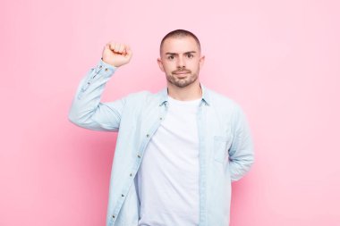 Genç yakışıklı adam kendini ciddi, güçlü ve asi hissediyor yumruğunu kaldırıyor, protesto ediyor ya da yassı duvara karşı devrim için savaşıyor.