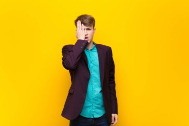 Genç sarışın adam uykulu, sıkılmış ve esniyor, baş ağrısı ve yüzünün yarısını kaplayan yassı duvar