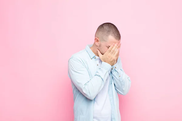 年轻英俊的男子双手捂住眼睛 脸上露出忧郁 哭泣的表情 侧视着平坦的墙壁 — 图库照片