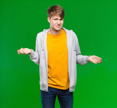 Sarışın genç adam kendini cahil ve şaşkın hissediyor, hangi seçeneği seçeceğinden emin değil, kroma anahtarına karşı merak içinde.