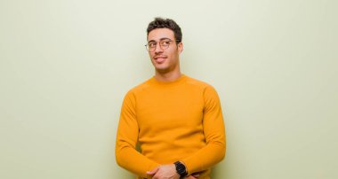 Genç Arap adam merak ediyor, mutlu düşünceler ve fikirler düşünüyor, hayal kuruyor, düz duvara uzayı kopyalamak istiyor.