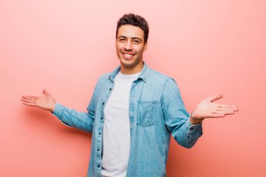 Genç Arap adam mutlu, kibirli, gururlu ve kendinden memnun görünüyor. Pembe duvara karşı kendini bir numara gibi hissediyor.