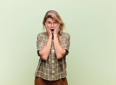  Şok olmuş ve korkmuş hissediyorum, ağzı açık ve elleri yanaklarında korkmuş görünüyor.