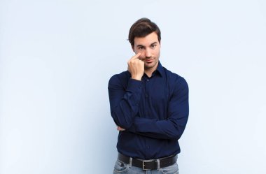 Genç yakışıklı adam sana göz kulak oluyor, güvenmiyor, izliyor ve mavi duvara karşı tetikte oluyor.