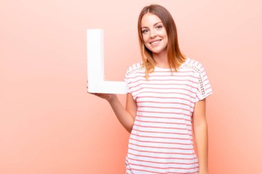 Genç, güzel kızıl saçlı kadın heyecanlı, mutlu, neşeli, alfabenin L harfini tutan bir kelime ya da cümle oluşturmak için..