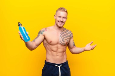 Genç sarışın güçlü adam neşeyle gülümsüyor sıcak, dostça, sevgi dolu bir kucak veriyor, enerji içeceğiyle kendini mutlu ve sevimli hissediyor.