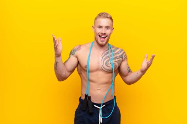 Genç güçlü sarışın adam kendini mutlu, şaşkın, şanslı ve şaşırmış hissediyor. Zaferi iki elini havaya kaldırarak kutluyor.