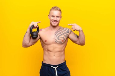 Genç, güçlü, sarışın, kendine güvenen, gülümseyen, pozitif, rahat, halterli bir adam.