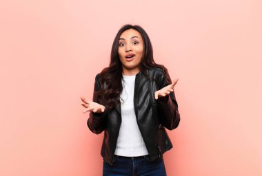 Genç, Latin, güzel bir kadın şok olmuş, şaşırmış, endişeli ve paniklemiş hissediyor. Stresli ve dehşete düşmüş bir şekilde düz duvara bakıyor.