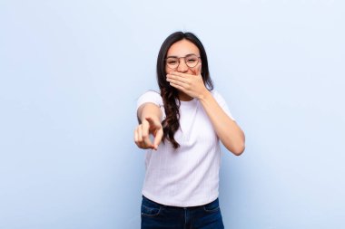 Genç Latin güzel kadın sana gülüyor, kamerayı işaret ediyor ve seninle dalga geçiyor ya da düz duvara karşı alay ediyor.