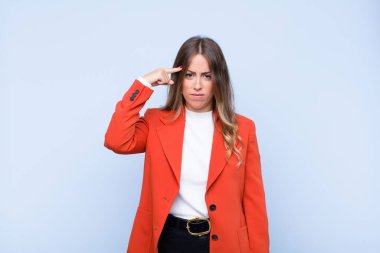 Genç ve güzel İspanyol kadın şaşkın ve şaşkın hissediyor. Deli, deli ya da mavi duvara karşı aklını kaçırmış olduğunu gösteriyor.