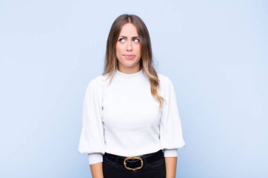 Şaşkın ve kafası karışmış görünen, bir sorunu çözmeye çalışan ya da mavi duvara karşı düşünen genç, güzel İspanyol bir kadın.