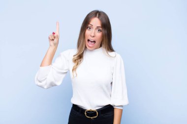 Genç, güzel İspanyol bir kadın bir fikri fark ettikten sonra mutlu ve heyecanlı bir dahi gibi hissediyor. Neşeli bir şekilde parmağını kaldırıyor. Evreka! mavi duvara yaslan