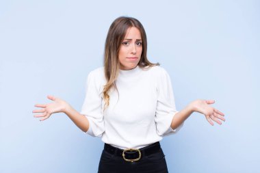 Genç ve güzel İspanyol kadın şaşkın ve kafası karışmış hissediyor. Doğru cevap ya da karardan emin değil. Mavi duvara karşı bir seçim yapmaya çalışıyor.