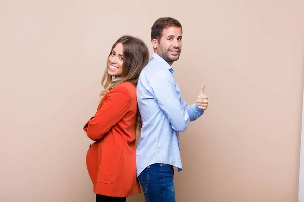 一对年轻漂亮的夫妇靠着米色的平板墙 — 图库照片