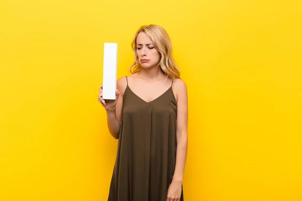 stock image young blonde woman sad, depressed, unhappy, holding the letter I of the alphabet to form a word or a sentence.