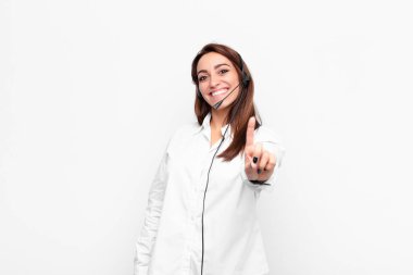 Genç ve güzel bir kadın gururla gülümsüyor ve gururla birinci pozunu veriyor. Kulaklığı ve mikrofonu olan bir lider gibi hissediyor.