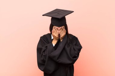 Genç Latin kız öğrenci üzgün, hayal kırıklığına uğramış, gergin ve depresif, iki eliyle yüzünü kaplayan, ağlayan