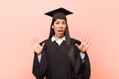 Genç Latin kız öğrenci sersemlemiş ve korkmuş hissediyor. Korkutucu bir şeyden korkuyor. Elleri açık ve uzak durun diyor.