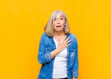 Yaşlı ya da orta yaşlı güzel bir kadın şok olmuş ve şaşırmış hissediyor, gülümsüyor, el ele tutuşuyor, mutlu oluyor ya da minnettarlık gösteriyor.