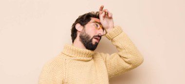 Stresli, yorgun ve hayal kırıklığına uğramış, alnından ter damlayan, umutsuz ve bitkin hisseden genç bir adam.