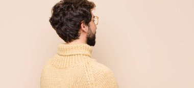 Profil görünümünde genç havalı bir adam uzayı kopyalamaya çalışıyor, düşünüyor, hayal ediyor ya da düz duvara karşı hayal kuruyor.