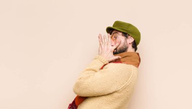 Genç havalı sakallı adam korkmuş ya da utanmış hissediyor, gözleri yarı kapalı ya da elleri kapalı dikizliyor ya da gözetliyor.