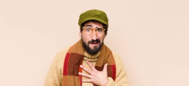 Genç havalı sakallı adam şok olmuş ve şaşırmış hissediyor, gülümsüyor, el ele tutuşuyor, mutlu ya da şükran duyuyor.