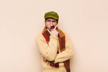 Genç, sakallı, ağzı ve gözleri açık, elleri çenesinde, hoş olmayan bir şok geçiriyor, ne ya da vay canına diyor.