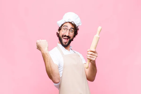 若い狂気のパン屋の男ピンクの壁に対する調理器具で — ストック写真