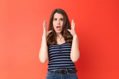 Genç ve güzel bir kadın ellerini havaya kaldırarak bağırıyor. Öfkeli, sinirli, gergin ve kırmızı duvara karşı üzgün hissediyor.