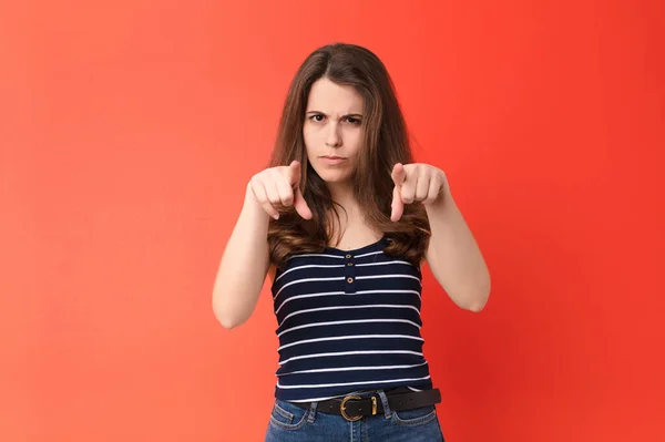 若い女性は指と怒りの表情でカメラを前に向け赤い壁に対して義務を果たすように言いました — ストック写真