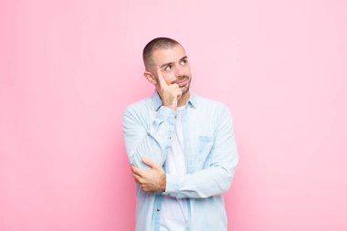 Yoğunlaşmış bakışlı genç yakışıklı adam, şüpheli bir ifadeyle merak ediyor, düz duvara bakıp duruyor.