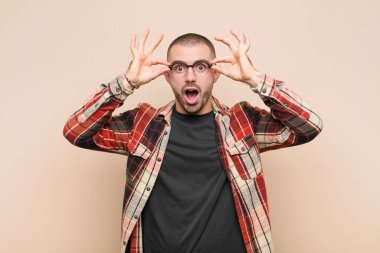 Genç yakışıklı adam şok olmuş, şaşırmış ve şaşırmış hissediyor. Elinde hayrete düşmüş, inanmayan bir şekilde düz duvara bakıyor.