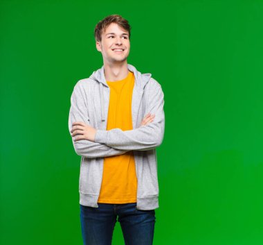 Genç sarışın adam mutlu, gururlu ve umutlu, merak eden ya da düşünen, kollarını kroma tuşuna dayamış çapraz kollarıyla boşluğu arayan