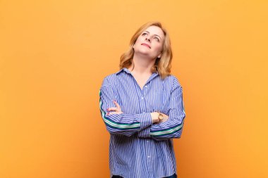 Orta yaşlı bir kadın mutlu, gururlu ve umutlu, merak ediyor ya da düşünüyor, çapraz kollarla fotokopi çekmeyi bekliyor.