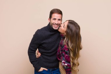 Genç ve güzel bir çift bej düz duvara karşı