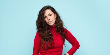 Genç, güzel bir kadın şüpheye düşüyor ya da düşünüyor, dudağını ısırıyor ve kendini güvensiz ve gergin hissediyor, mavi duvara karşı boşluğu kopyalamak istiyor.