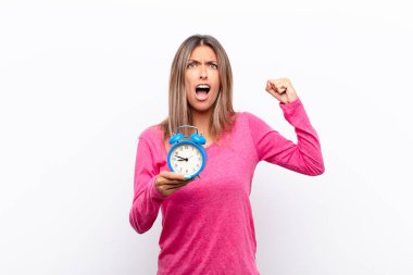 Genç ve güzel bir kadın sinirli bir ifadeyle ya da yumruklarıyla bağırıyor. Çalar saati tutarak başarıyı kutluyor..
