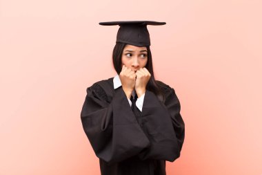 Genç Latin kız öğrenci endişeli, stresli ve korkmuş görünüyor, tırnak yiyor ve yanal fotokopi için yer arıyor.