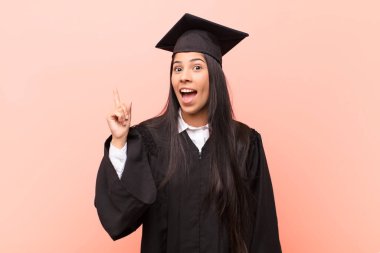 Genç Latin kız öğrenci bir fikri fark ettikten sonra mutlu ve heyecanlı bir dahi gibi hissediyor, neşeli bir şekilde parmağını kaldırıyor, eureka!