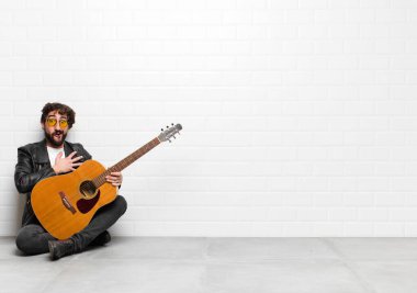 Genç müzisyen şok olmuş ve şaşırmış hissediyor, gülümsüyor, el ele tutuşuyor, gitar, rock 'n roll konseptiyle minnettarlık göstermekten mutlu.