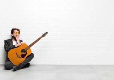 Genç müzisyen tembelce esniyor, uykulu görünüyor, yorgun ve gitar, rock 'n roll konseptinden sıkılmış.