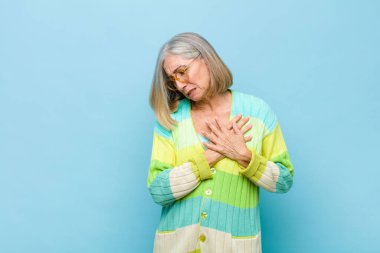 Yaşlı ya da orta yaşlı güzel bir kadın üzgün, yaralı ve kalbi kırık görünüyor, iki elini de kalbe yakın tutuyor, ağlıyor ve bunalımda.