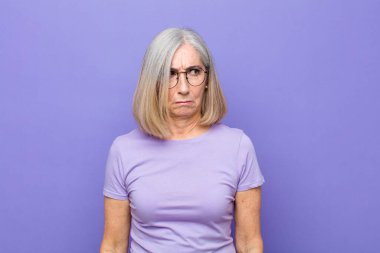 Yaşlı ya da orta yaşlı güzel bir kadın üzgün, üzgün ya da kızgın ve olumsuz bir tavır takınıyor, anlaşmazlık içinde kaşlarını çatıyor.