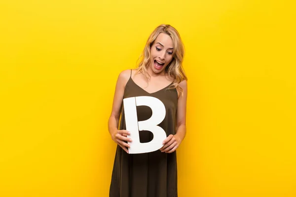 Young Blonde Woman Surprised Shocked Amazed Holding Letter Alphabet Form — Stock Photo, Image