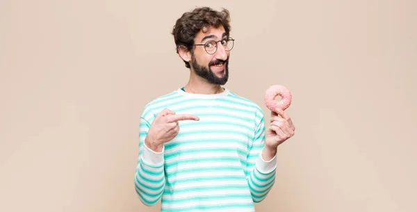 平らな壁に砂糖ピンクのドーナツを着た若いクールな男 — ストック写真