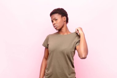 Genç ve güzel siyah kadın stresli, endişeli, yorgun ve hayal kırıklığına uğramış, gömlek yakalı, pembe duvara karşı sorunlu görünüyor.